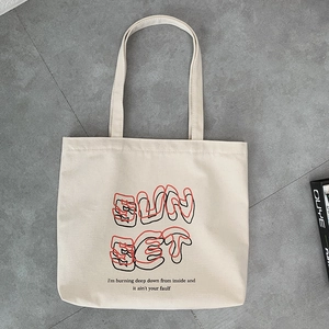 Close-up of cream canvas tote bag showing the SUN SET artistic text and fabric texture