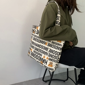 Detail of canvas tote bag featuring orange cartoon bear and handsome print on wide strap