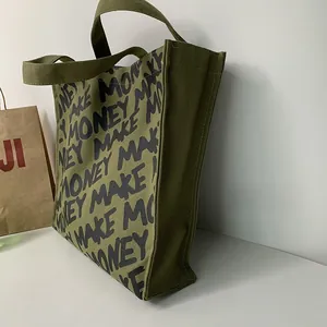 Detail view of olive green canvas tote bag with black Make Money print and side gusset