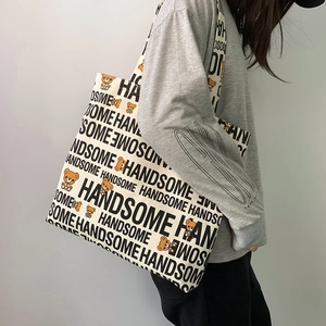 Detail of canvas tote bag featuring handsome lettering and orange cartoon bear print