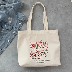 Detail of off-white canvas tote bag featuring Sunset print with denim jacket background