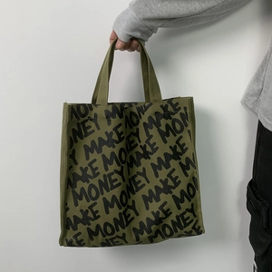 Close-up of military green canvas tote bag with black Make Money graffiti print