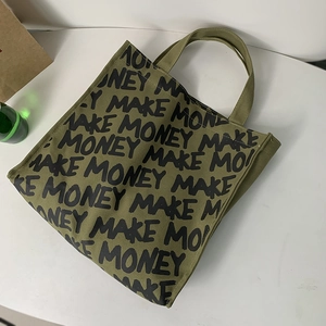 Close-up of military green canvas tote bag featuring MAKE MONEY graffiti print lettering