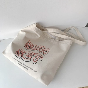 Detail of minimalist cream canvas tote bag with artistic SUNSET graphic and letter print