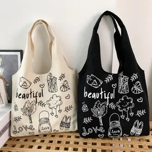 Dettaglio di borse tote in tela bianca e nera con illustrazioni artistiche e testo