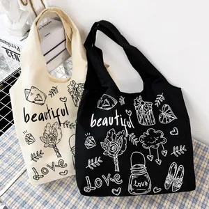 Dettaglio borse tote in tela beige e nera con stampe graffiti a cuore e manici robusti