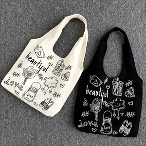 Dettaglio dei motivi graffiti fatti a mano su borse tote in tela nera e beige naturale