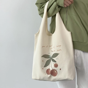 Detail of off-white canvas tote bag with red cherry prints and artistic green lettering