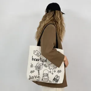 Dettaglio della borsa tote in tela beige con disegni a tratti e scritte artistiche