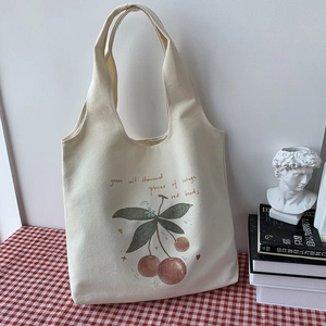 Detail of canvas tote bag featuring cherry print on a red checkered tablecloth