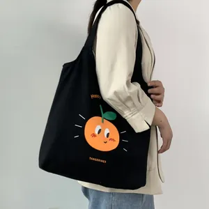 Dettaglio della borsa tote in tela nera con stampa mandarine e blazer beige