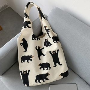Detail of canvas tote bag with black bear pattern on a cozy gray fabric sofa