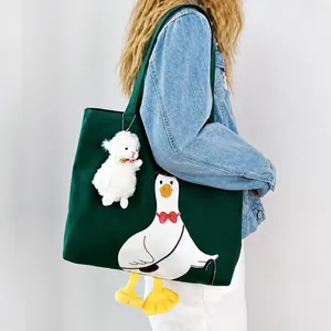 Detail of dark green canvas tote featuring a white duck print and small sheep plush charm