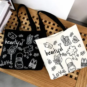 Dettaglio delle borse tote in tela con disegni floreali fatti a mano e stampe di lettere