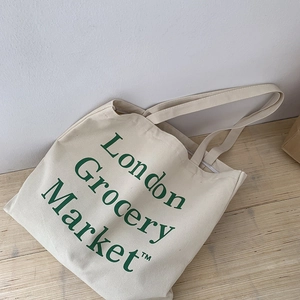 Minimalist canvas tote bag with green London Grocery Market print on wooden table