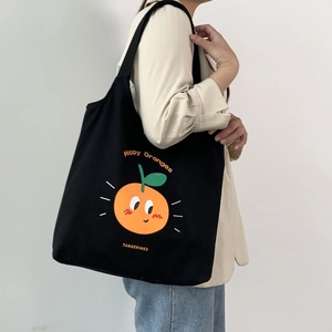 Dettaglio della borsa tote in tela nera con stampa di agrumi arancioni e scritta vivace