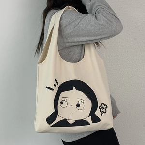 Detail der cremefarbenen Canvas-Tragetasche mit schwarzem Cartoon-Mädchen-Print und Tragegurt