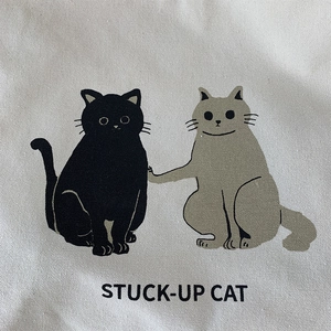 Close-up of canvas bag featuring cute cartoon cats and Stuck-Up Cat printed text