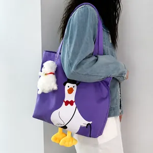 Detail of cute purple canvas tote bag with goose print and plush alpaca charm
