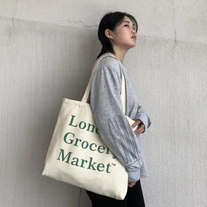 Detailed side view of off-white canvas tote bag with London Grocery Market print