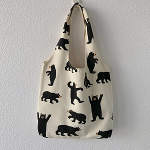 Detailed view of canvas tote bag featuring all-over black bear prints and soft fabric texture
