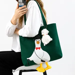 Detail of dark green canvas tote bag with cartoon goose and plush sheep pendant