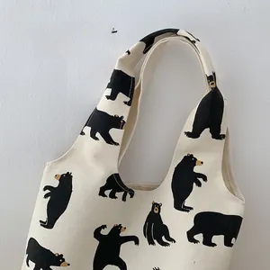 Detail showing the comfortable wide shoulder strap of the white canvas dog pattern tote bag