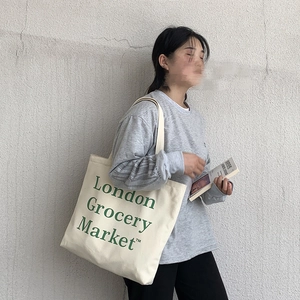 Close-up of cream canvas tote bag with green London Grocery Market letter print