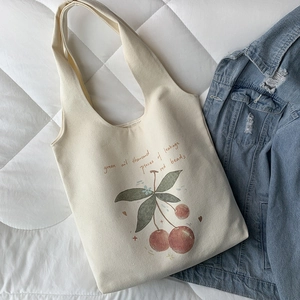 Detailed macro view of cherry print and artistic lettering on off-white canvas tote bag