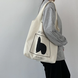 Detail of off-white canvas tote bag featuring minimalist animal graphic and shoulder strap