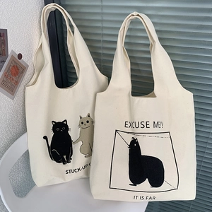 Detail of off-white canvas tote bags with cute cat and alpaca prints on a white chair