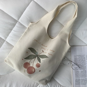 Detail of off-white canvas tote bag featuring cherry illustration and soft cotton texture