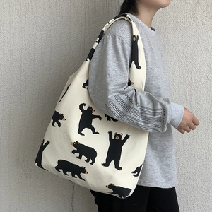 Detail of a large cream canvas tote bag featuring cute black bear prints for daily use