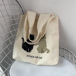 Detailed macro view of the cream canvas tote bag featuring cute cat print illustrations