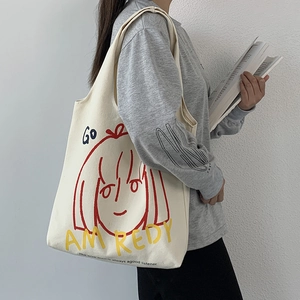 Artistic canvas tote bag with girl graphics and shoulder strap shown in style