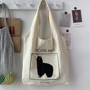 Close-up of canvas tote bag featuring an alpaca illustration hanging on a wall hook