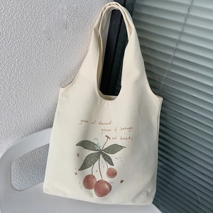 Detail of minimalist cream canvas tote bag featuring a realistic cherry print and text