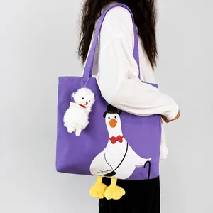 Detail of purple canvas tote bag with cartoon duck print and fluffy lamb keychain accessory