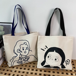 Detail von cremefarbenen Canvas-Taschen mit Illustrationen auf einer Holzbank