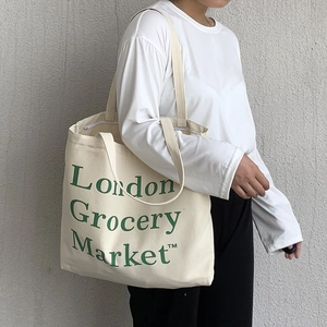Detail of cream canvas tote bag featuring green London Grocery Market text and sturdy handles