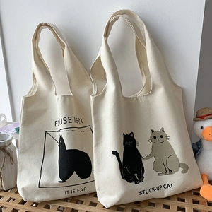Detail of canvas tote bags featuring cute cat illustrations and artistic English text