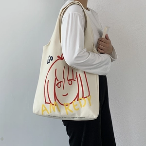 Detail of artistic canvas tote bag featuring red line girl illustration and bold letters