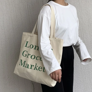 Detail of a large off-white canvas tote bag with green London Grocery Market print