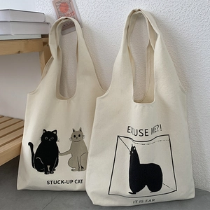 Close-up of canvas tote bags featuring cute cat illustrations and artistic typography