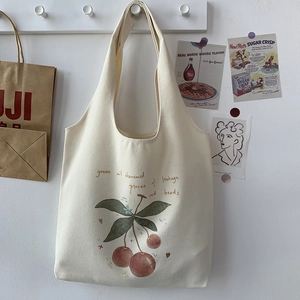 Detail of off-white canvas tote bag with hand-drawn cherry illustration and durable straps