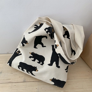 Detailed top view of off-white canvas tote bag featuring cute black cartoon bear prints