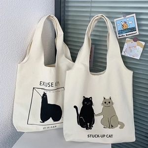 Close-up of minimalist cat illustration and slogan on white canvas tote bag