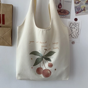 Close-up of canvas tote bag featuring aesthetic cherry prints and woven texture details