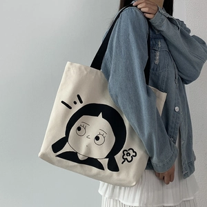 Detail der cremeweißen Canvas-Einkaufstasche mit schwarzem Cartoon-Druck und Schultergurt