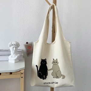 Detail of cute cat illustration and STUCK-UP CAT text on a cream canvas tote bag
